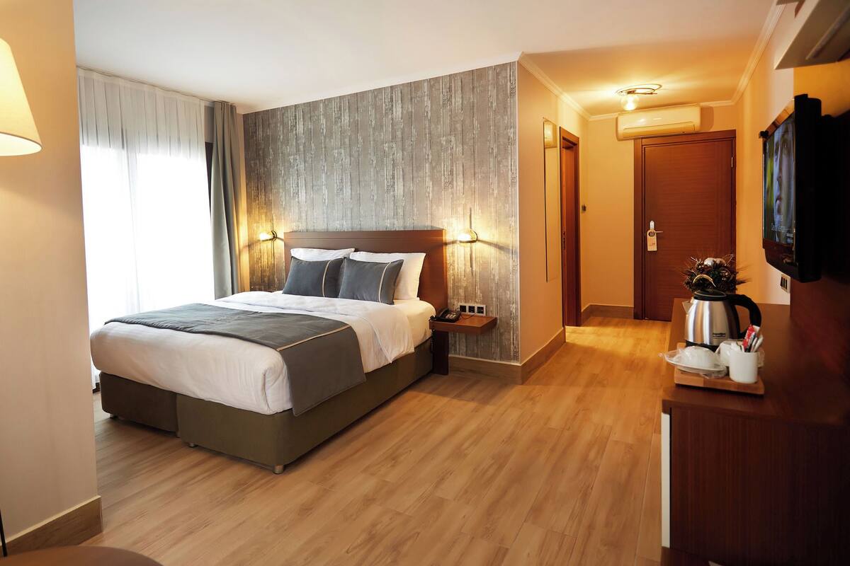 Een hotelkamer met een bed, nachtkastje, lamp en een televisie.
