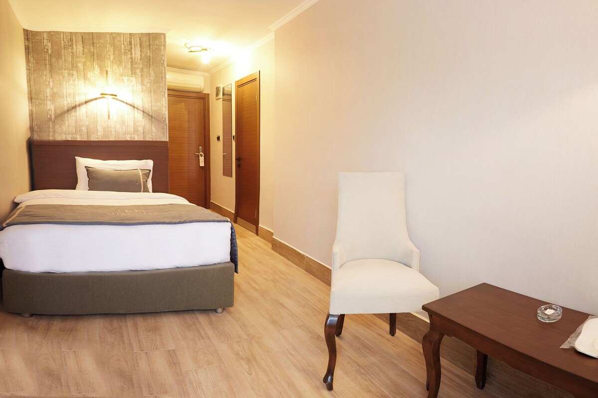 A hotel room with a bed, a chair, and a small table.