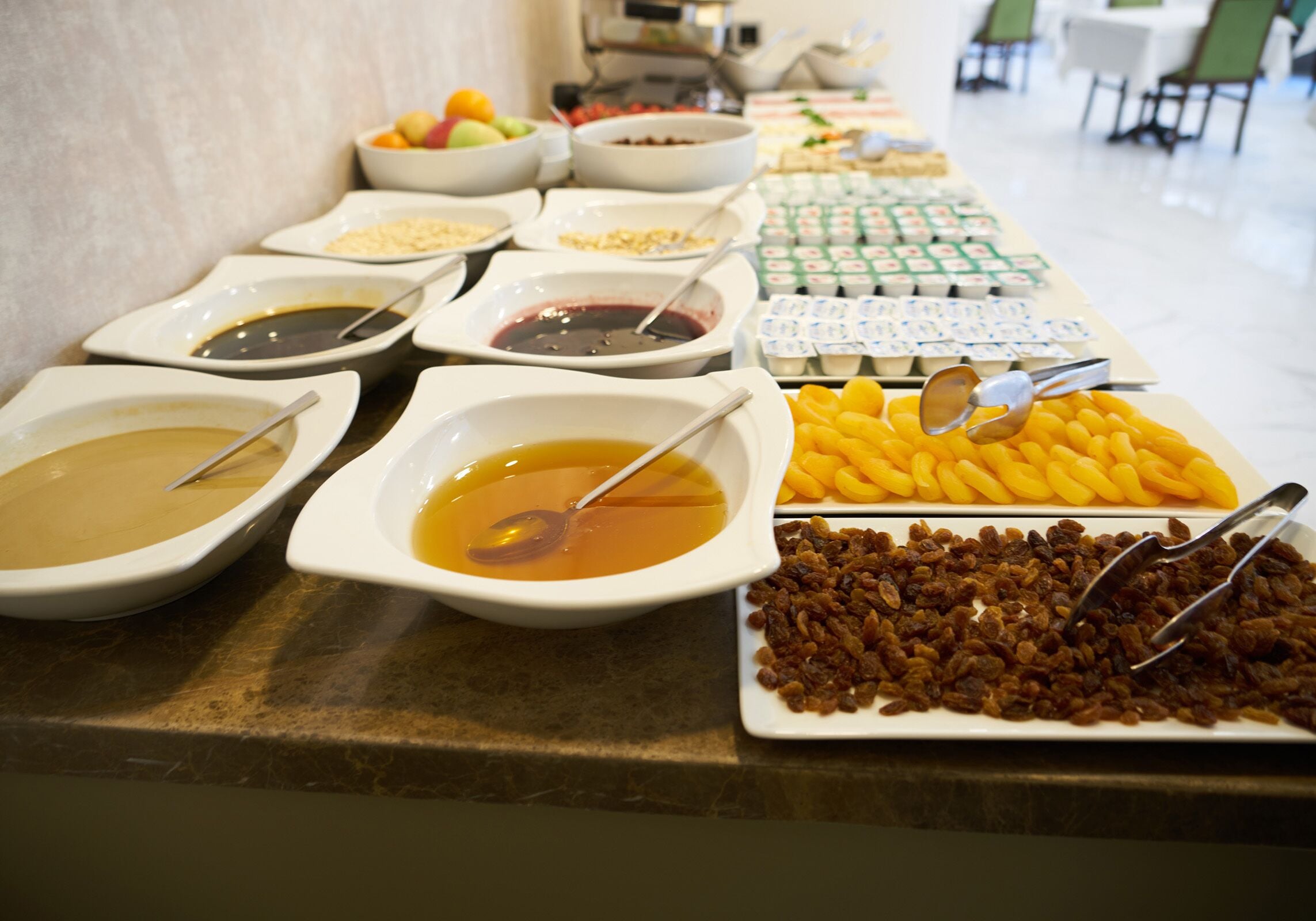 Una mesa de buffet con diversos alimentos, incluyendo tazones de sopa, un plato de pasas y una bandeja de queso.