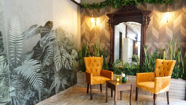 A room with two yellow armchairs, a wooden coffee table, and a mirror with an ornate frame. - Mira Otel Alsancak (Izmir)