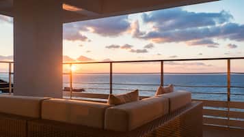 Relax in a serene oceanfront seating area with a wicker sofa and unobstructed views of the sea.