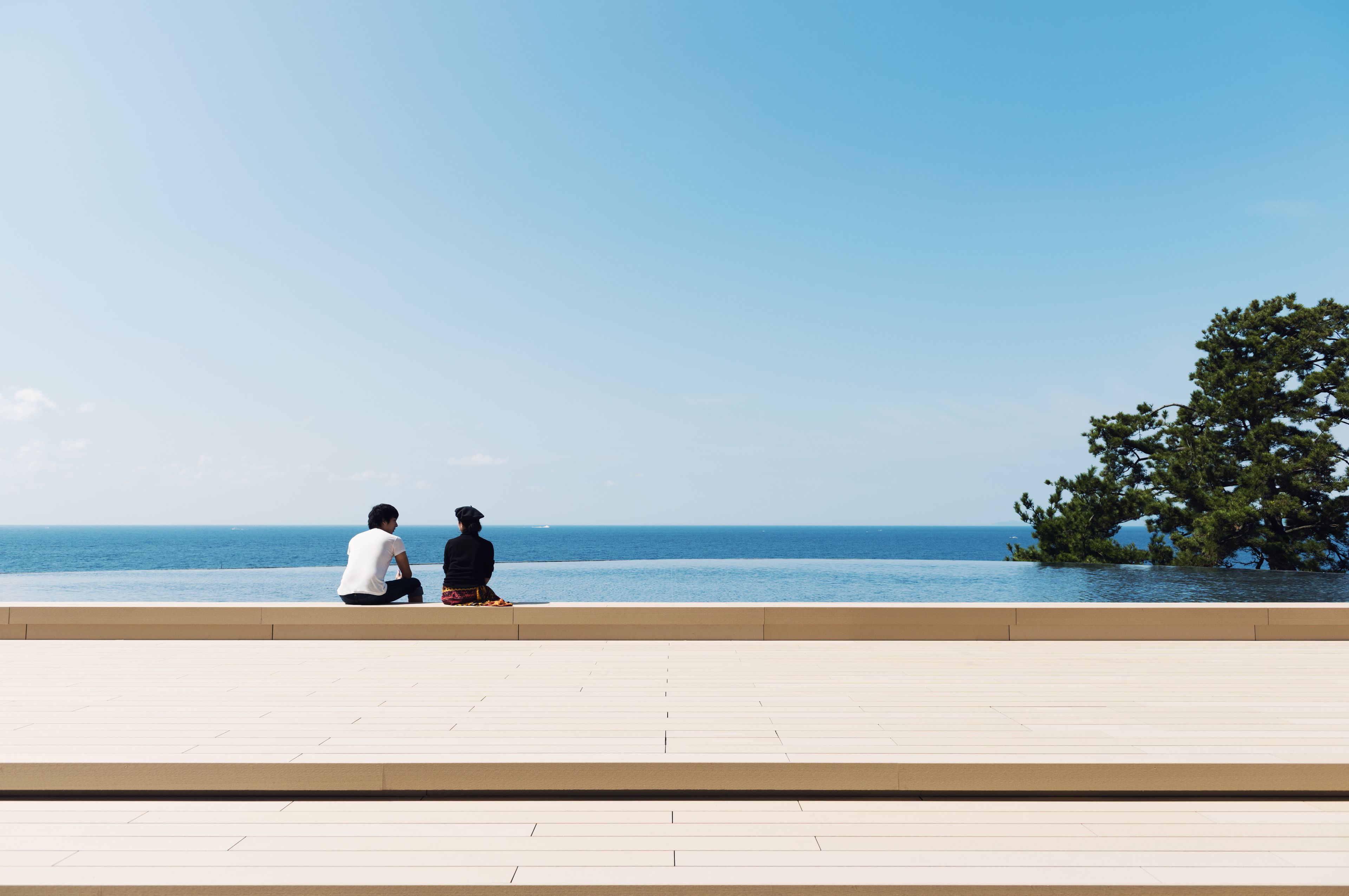 Deux personnes sont assises sur une terrasse donnant sur la mer.