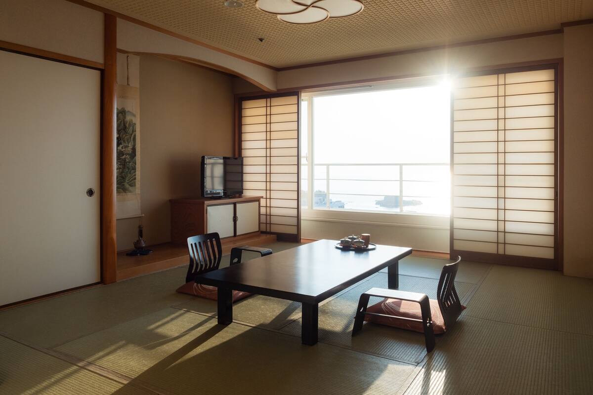 Ein traditioneller japanischer Raum mit Tatami-Böden, einem niedrigen Tisch und verschiebbaren Shoji-Türen.