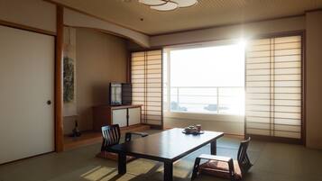 Una habitación japonesa tradicional con suelo de tatami, una mesa baja y puertas correderas shoji.