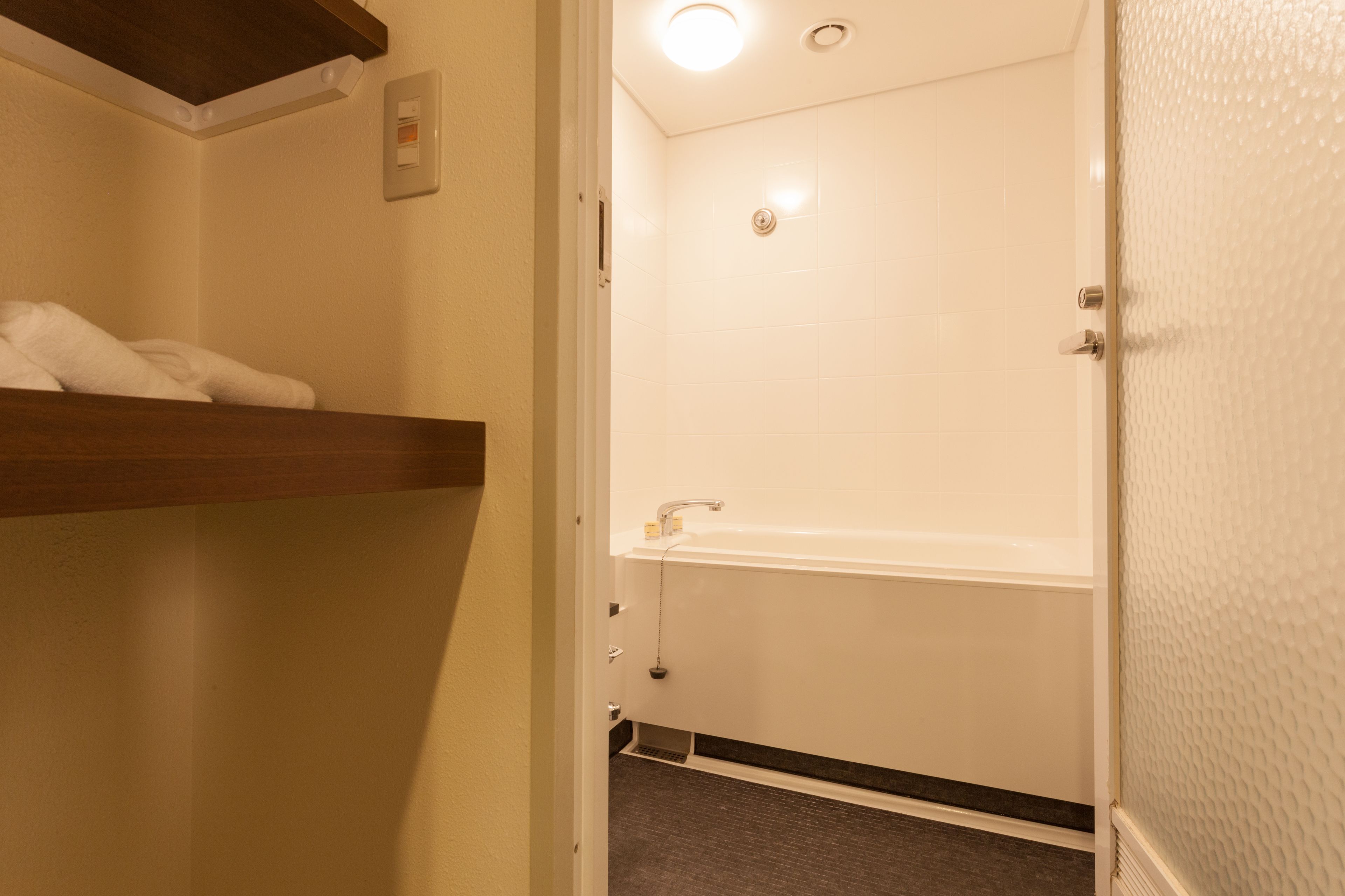 A bathroom with a white bathtub, a towel rack, and a shower.