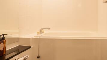 A modern bathroom with a large bathtub, a mirror, and a shower area.