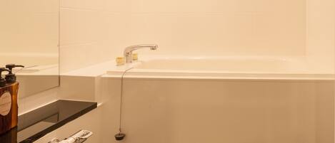 A modern bathroom with a large bathtub, a mirror, and a shower area.