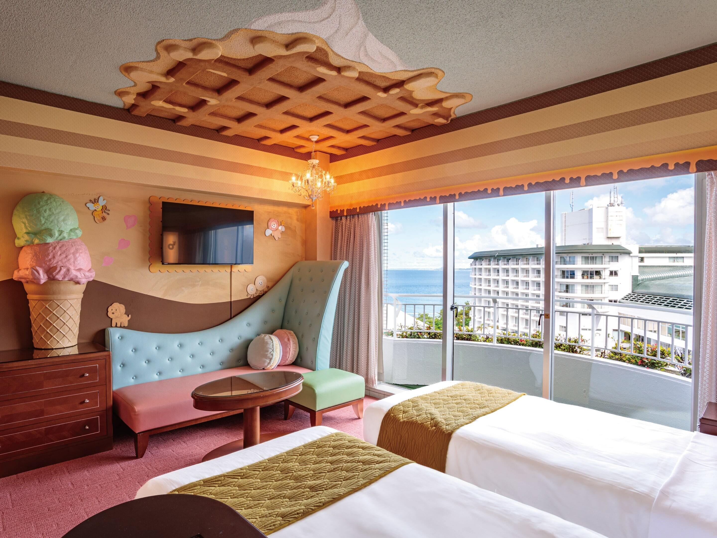 Habitación de hotel con un ventanal grande, un sofá, dos camas, un televisor y una decoración de pared.