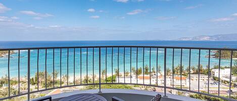 A balcony with a view of the ocean and a beach.