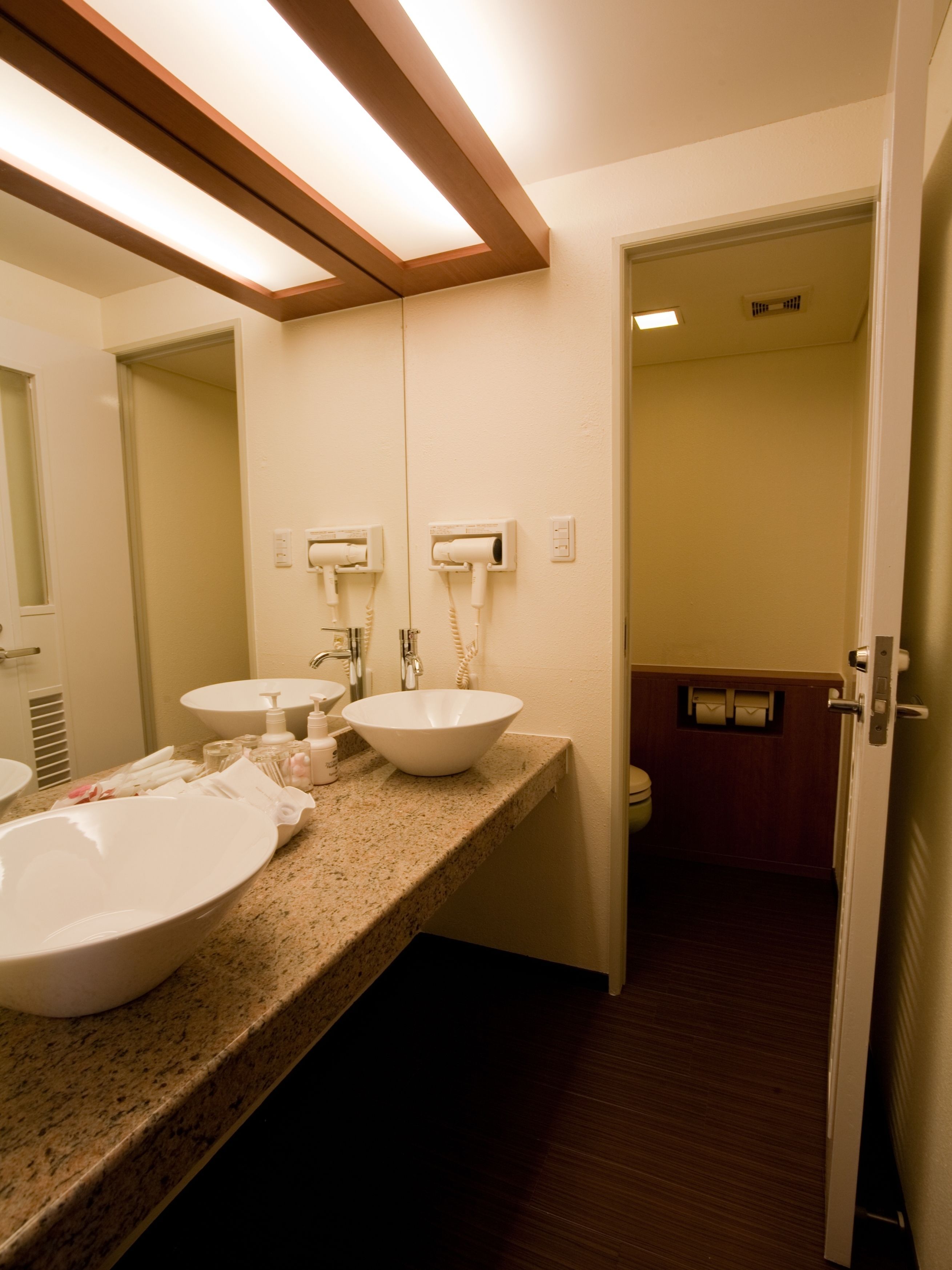 A bathroom with two sinks, a mirror, and a towel rack. There is a door leading to another room.