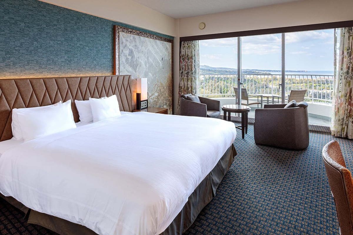 Una habitación de hotel con una cama grande, un área de descanso con una mesa y vistas a la ciudad.