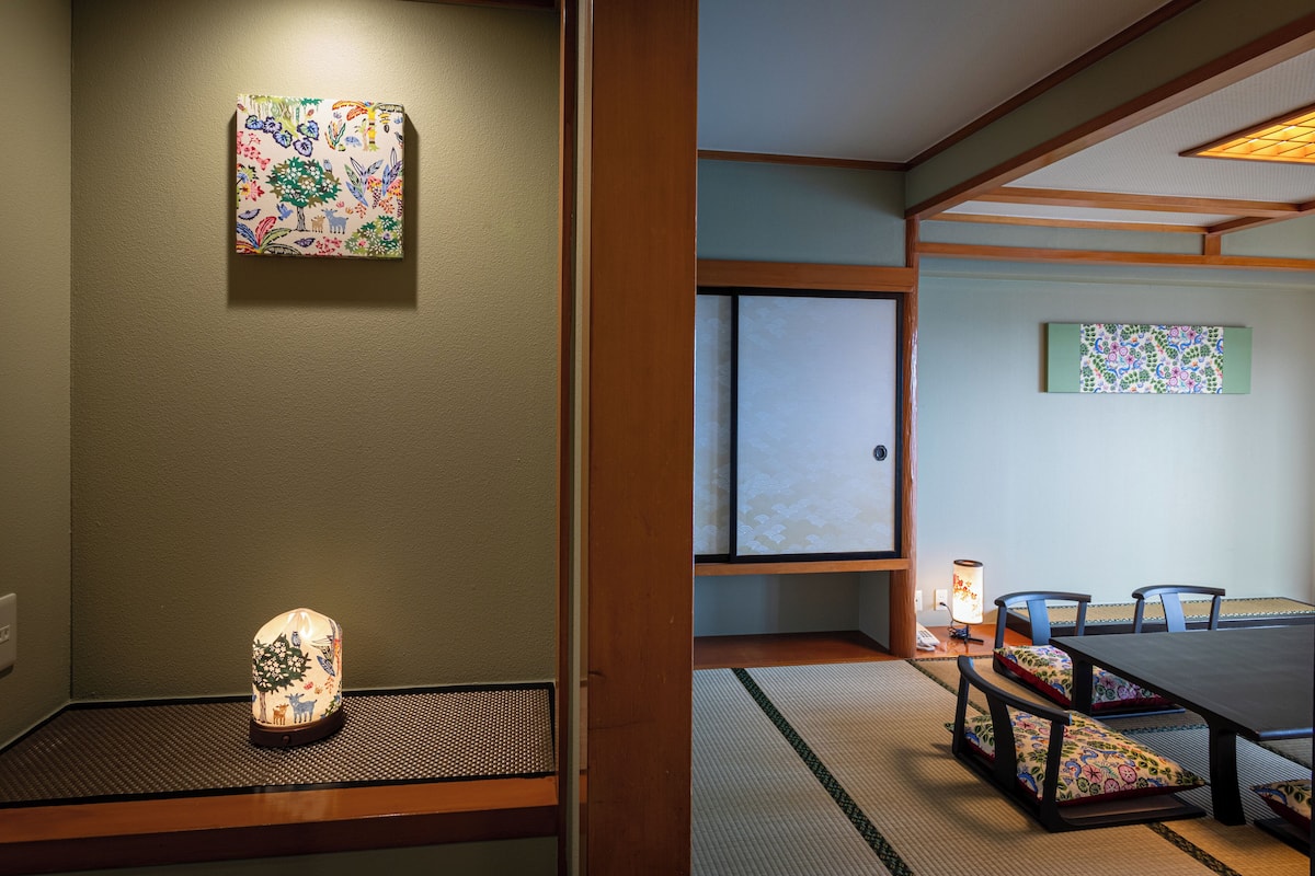 Una habitación japonesa tradicional con suelo de tatami, una mesa baja con cojines y una puerta corredera shoji.