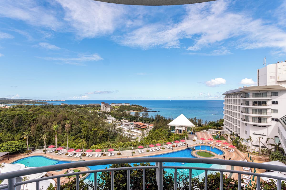 Un resort con piscina, sillas de descanso y vista al océano.