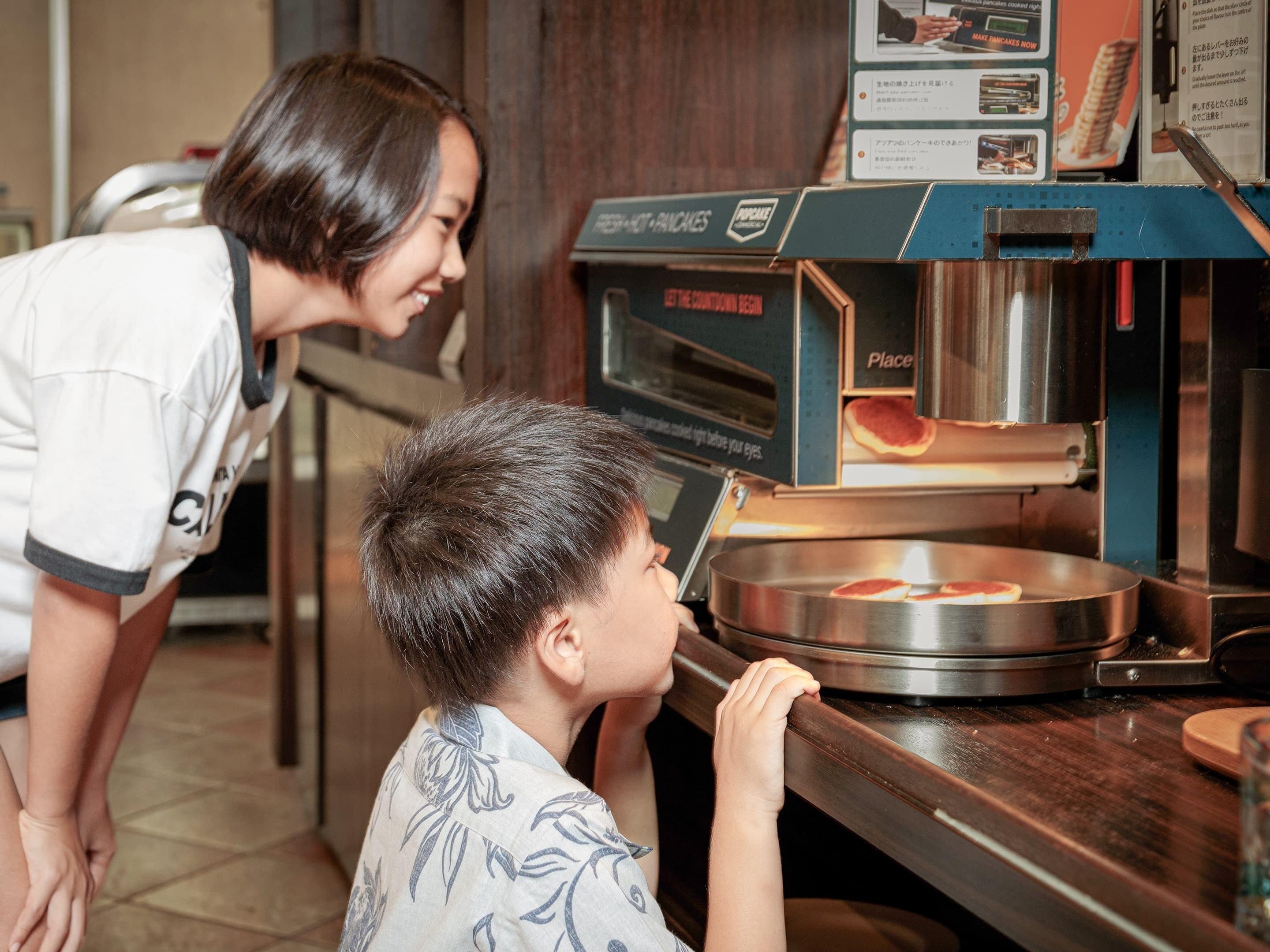 A person leaning over a counter with a pizza oven, observing the cooking process.