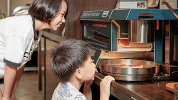 A person leaning over a counter with a pizza oven, observing the cooking process.