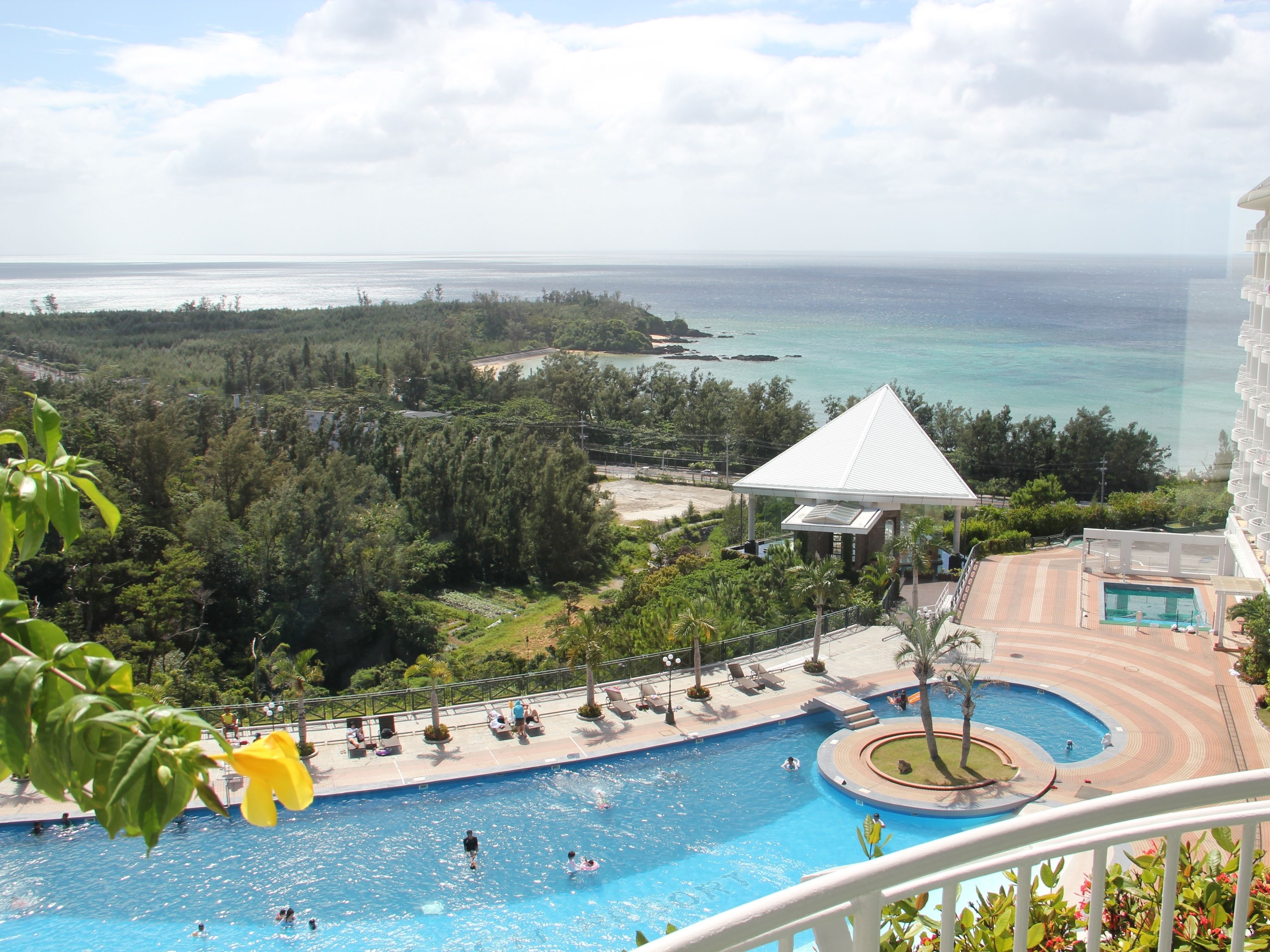 Área de piscina em resort com vista para o oceano, um gazebo e uma piscina circular.