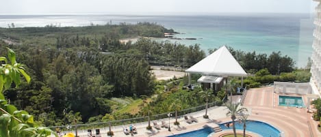 Zona de piscina en un resort con vista al océano, un pabellón y una piscina circular.