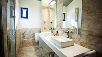 Un baño moderno con dos lavamanos, un espejo grande y una zona de ducha.