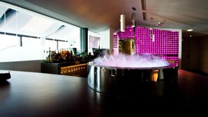 Een bar met een groot, rond, metalen bargedeelte en een zichtbare koffiemachine.