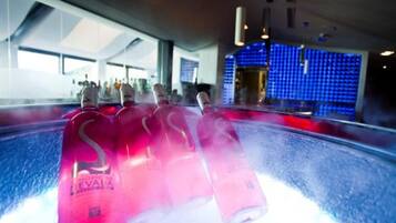 Un espace bar avec des bouteilles d’eau Evian et un mur illuminé en bleu en arrière-plan.