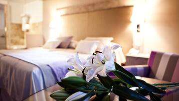 A hotel room with a bed, a glass table with flowers, and a sofa.