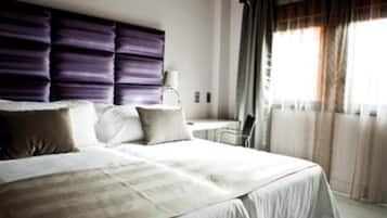 A modern hotel room with a large bed, a desk, and a chair.