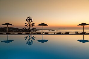 Una piscina al aire libre, sombrillas, sillones reclinables de piscina