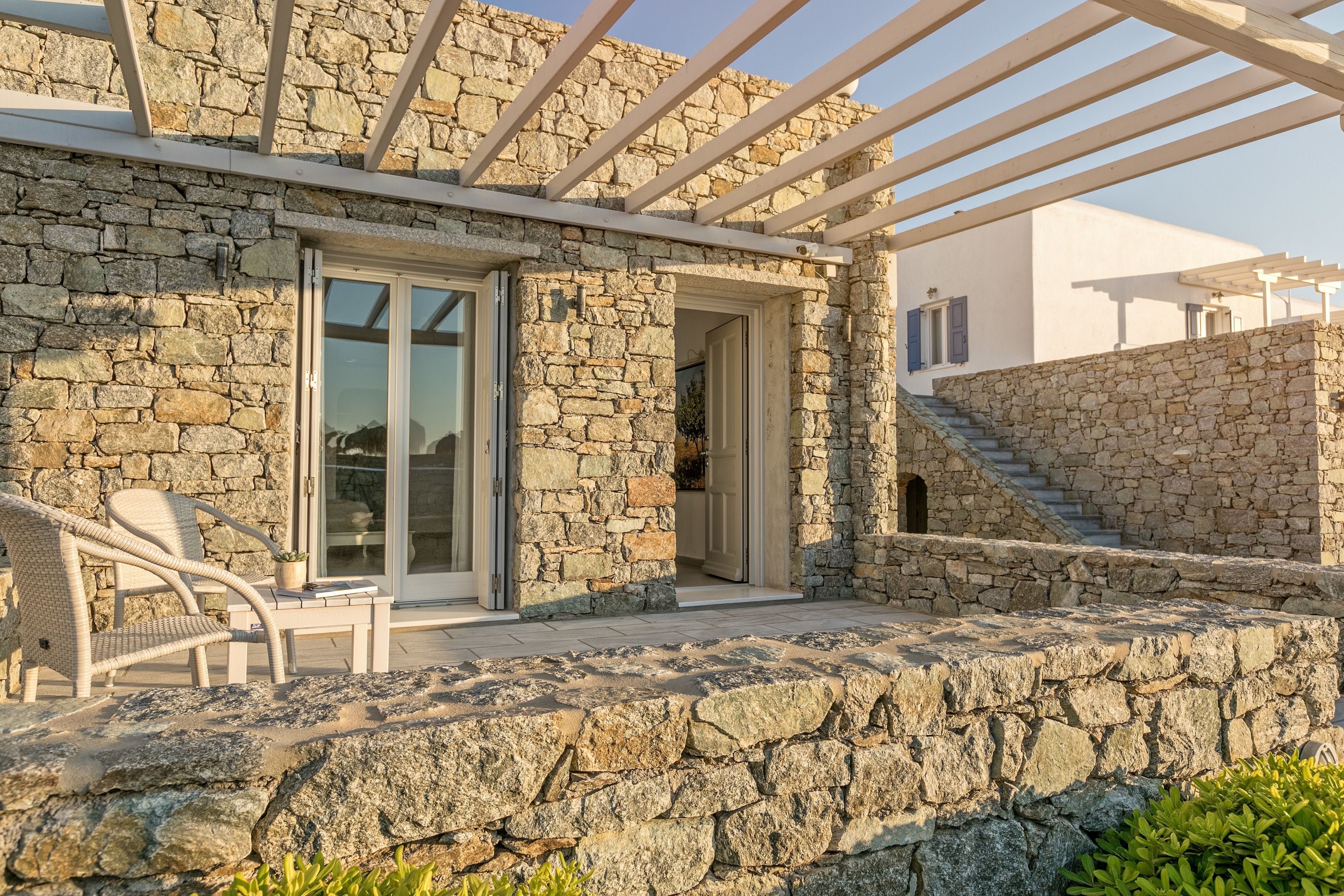 A stone building with a covered patio, outdoor seating, and a staircase leading to an upper level.