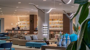 A modern hotel lobby with a bar area, seating arrangements, and a variety of decorative items.