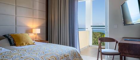 A hotel room with a bed, a desk, a chair, a TV, and a balcony with a view.