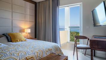 A hotel room with a bed, a desk, a chair, a TV, and a balcony with a view.