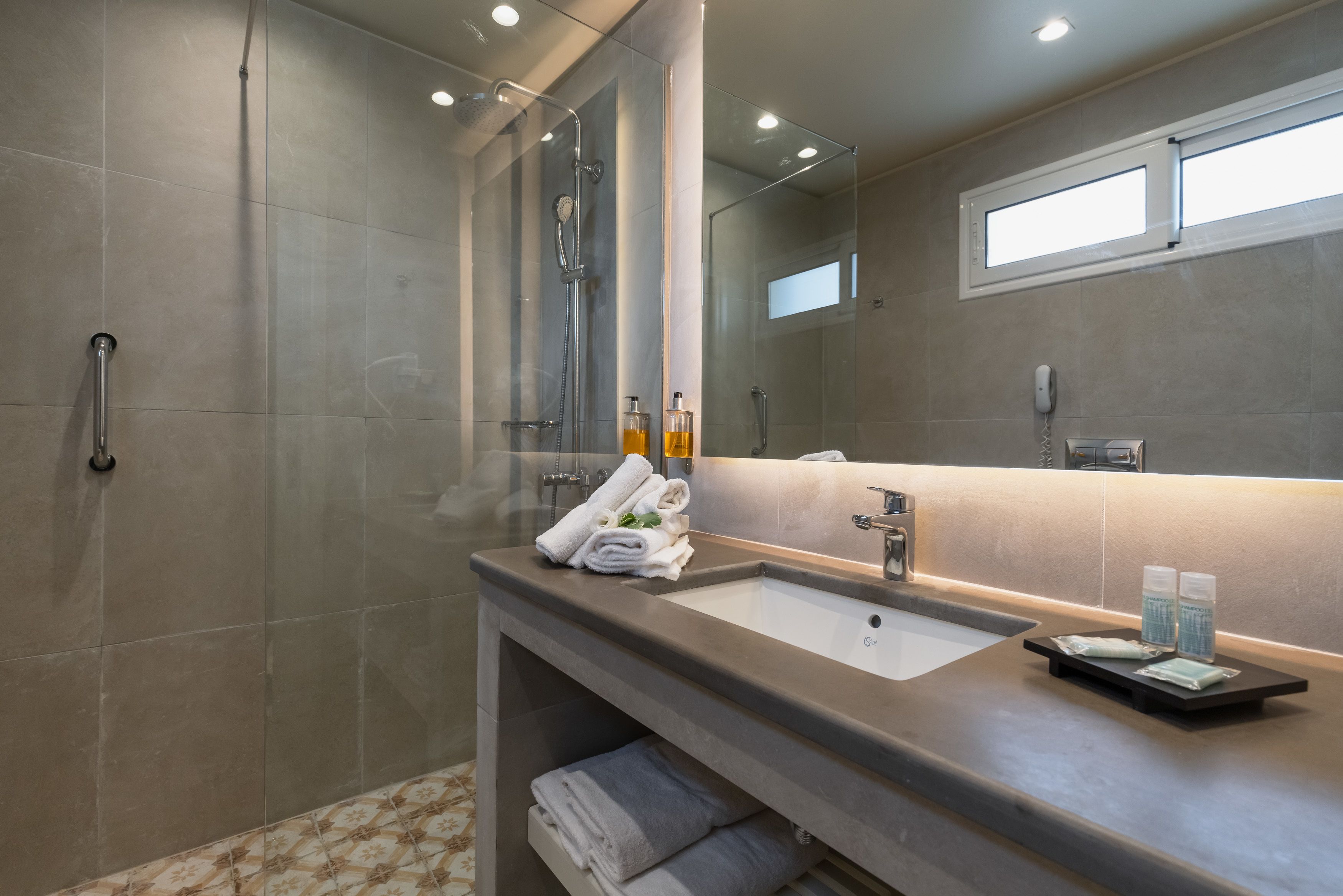 A modern bathroom with a glass shower enclosure, a vanity with a sink, and a mirror.
