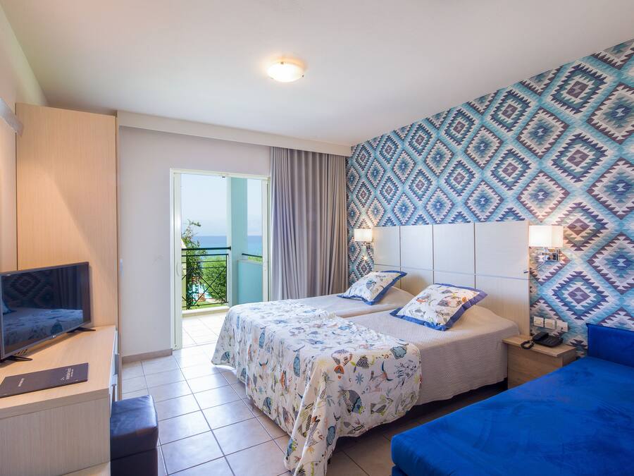 A hotel room with two beds, a TV, a desk, and a balcony with a view.