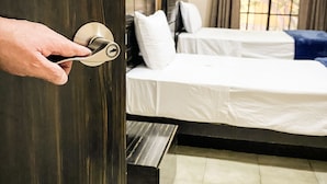 A hotel room with a bed, a bench, and a window with curtains.