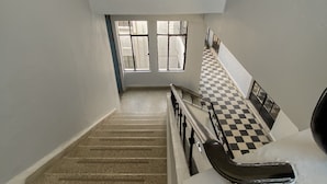A multi-level interior with a checkered floor, a staircase, and a railing.