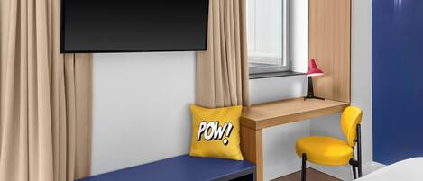 Une chambre d’hôtel moderne, équipée d’un lit, d’un bureau avec une chaise, d’un téléviseur fixé au mur et d’une fenêtre avec des rideaux.