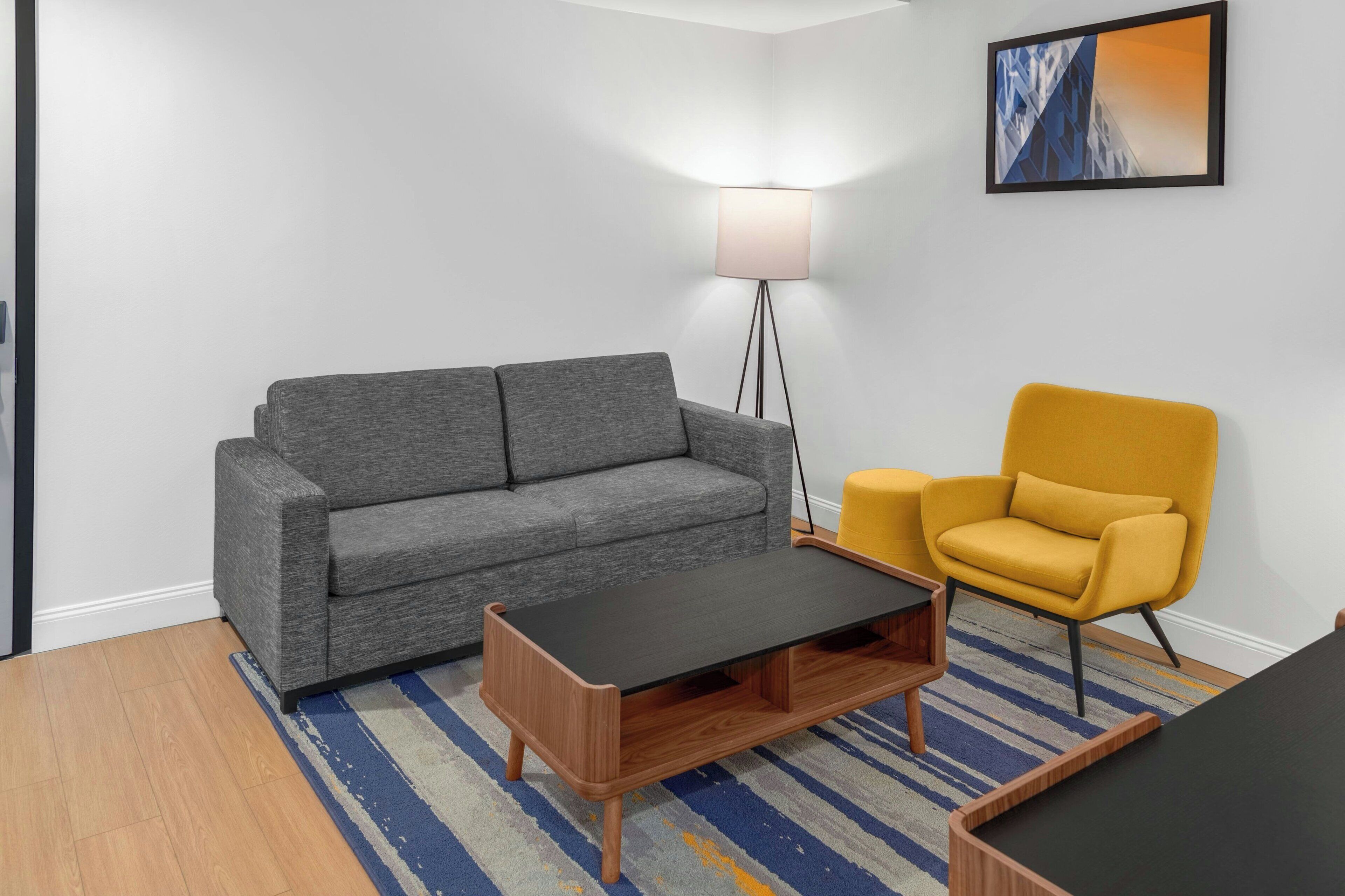 A modern living room with a grey sofa, a yellow armchair, a black coffee table, and a floor lamp.