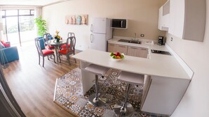 Une cuisine moderne avec un coin repas, un réfrigérateur, un four à micro-ondes et une machine à café.