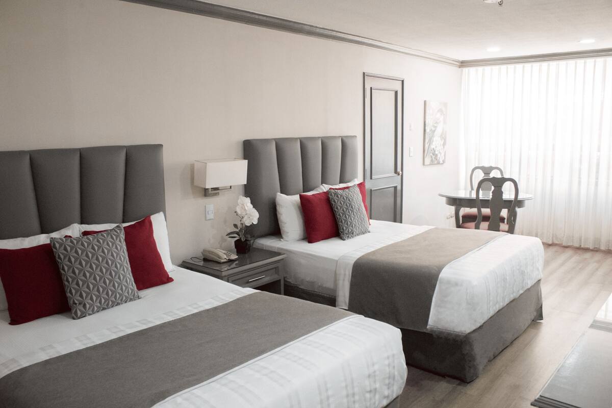 Ein Hotelzimmer mit zwei Betten, einem kleinen Tisch und einem Stuhl.