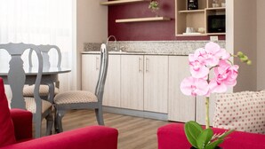 Un salon moderne avec une table ronde en verre, des fauteuils rouges et une orchidée en pot.