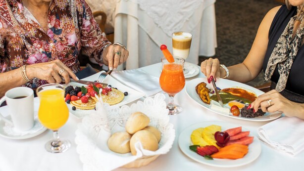 Une table avec des aliments pour le petit-déjeuner, notamment des fruits, des viennoiseries et une boisson au café.