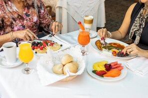 Et bord med morgenmadsprodukter, herunder frugt, kager og en kaffedrik.