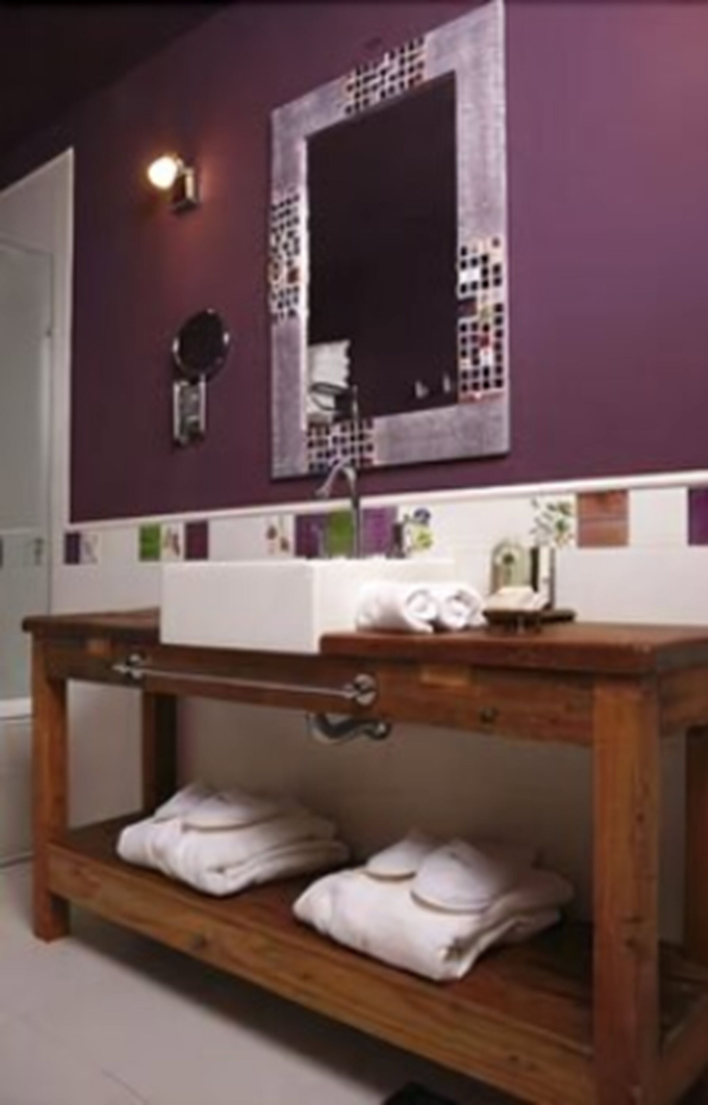 A bathroom with a wooden vanity, a white sink, and a mirror with a decorative frame.