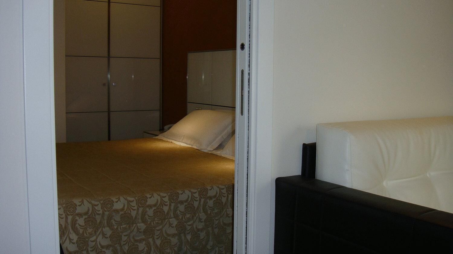 A bedroom with a bed, a wardrobe, and a nightstand.