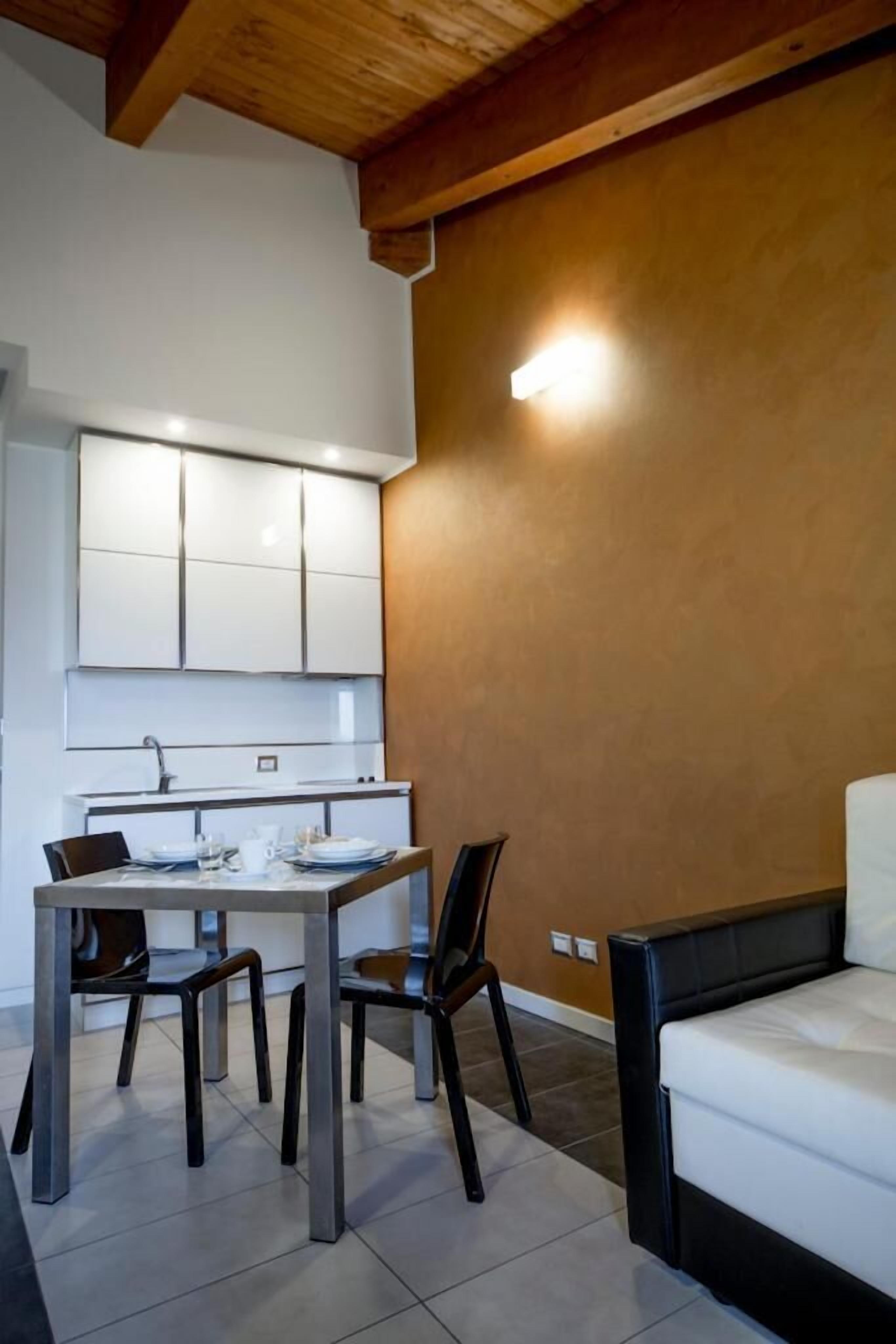 Una cocina compacta con armarios blancos y un comedor con mesa y sillas.