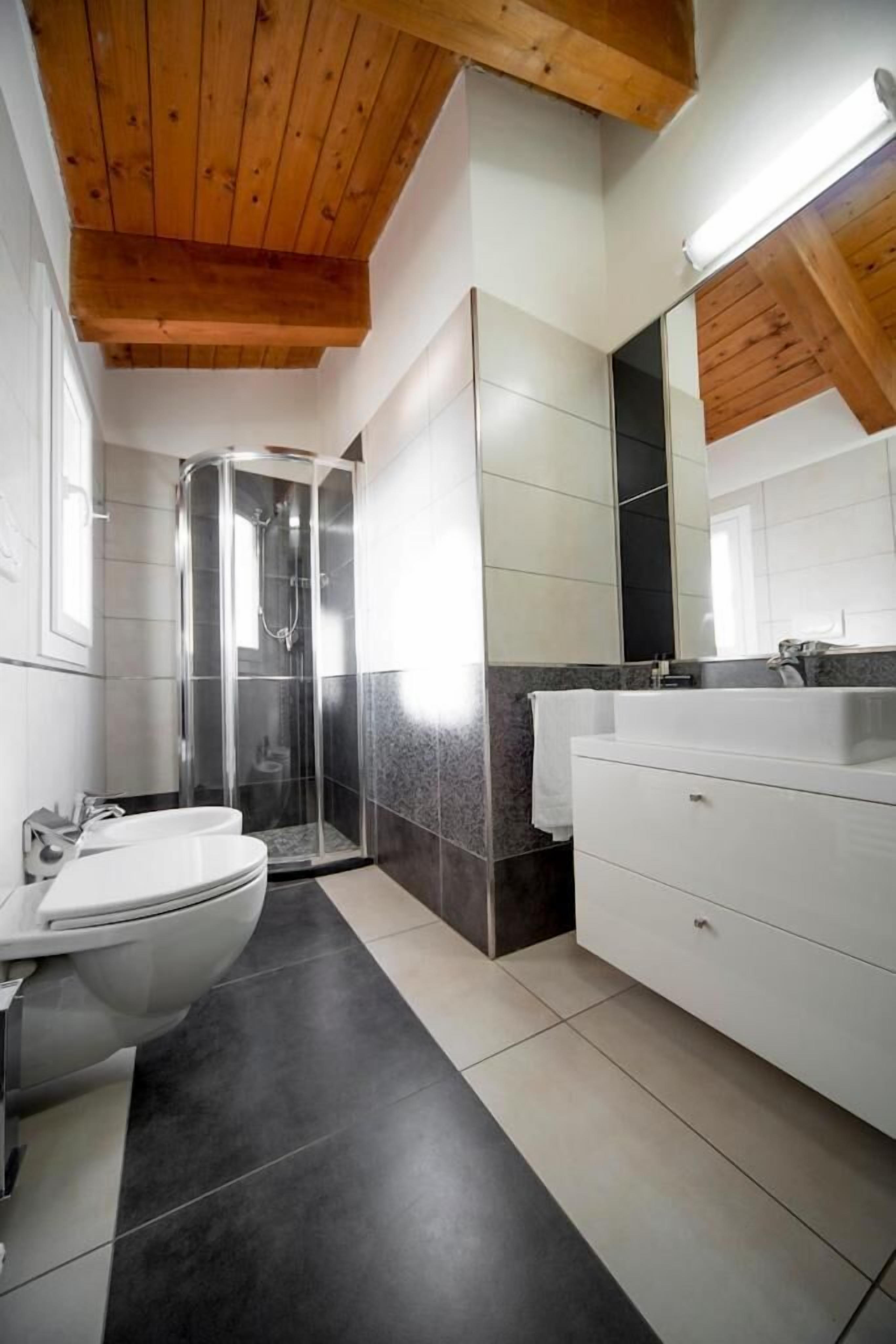 A modern bathroom with a shower, toilet, and vanity.