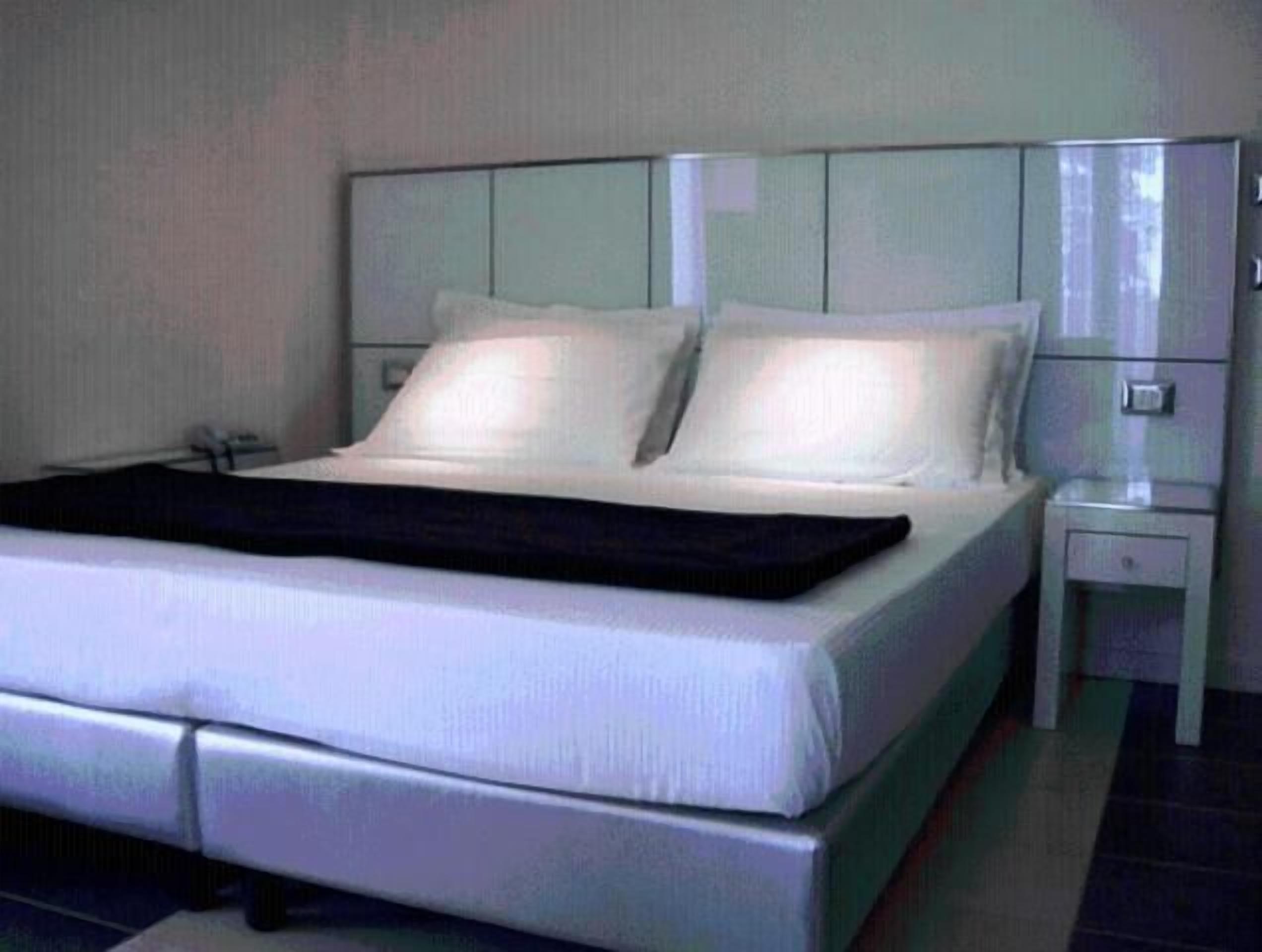 Una camera d'albergo moderna con un letto grande, un comodino e un tavolino.