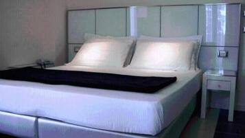 Una camera d'albergo moderna con un letto grande, un comodino e un tavolino.