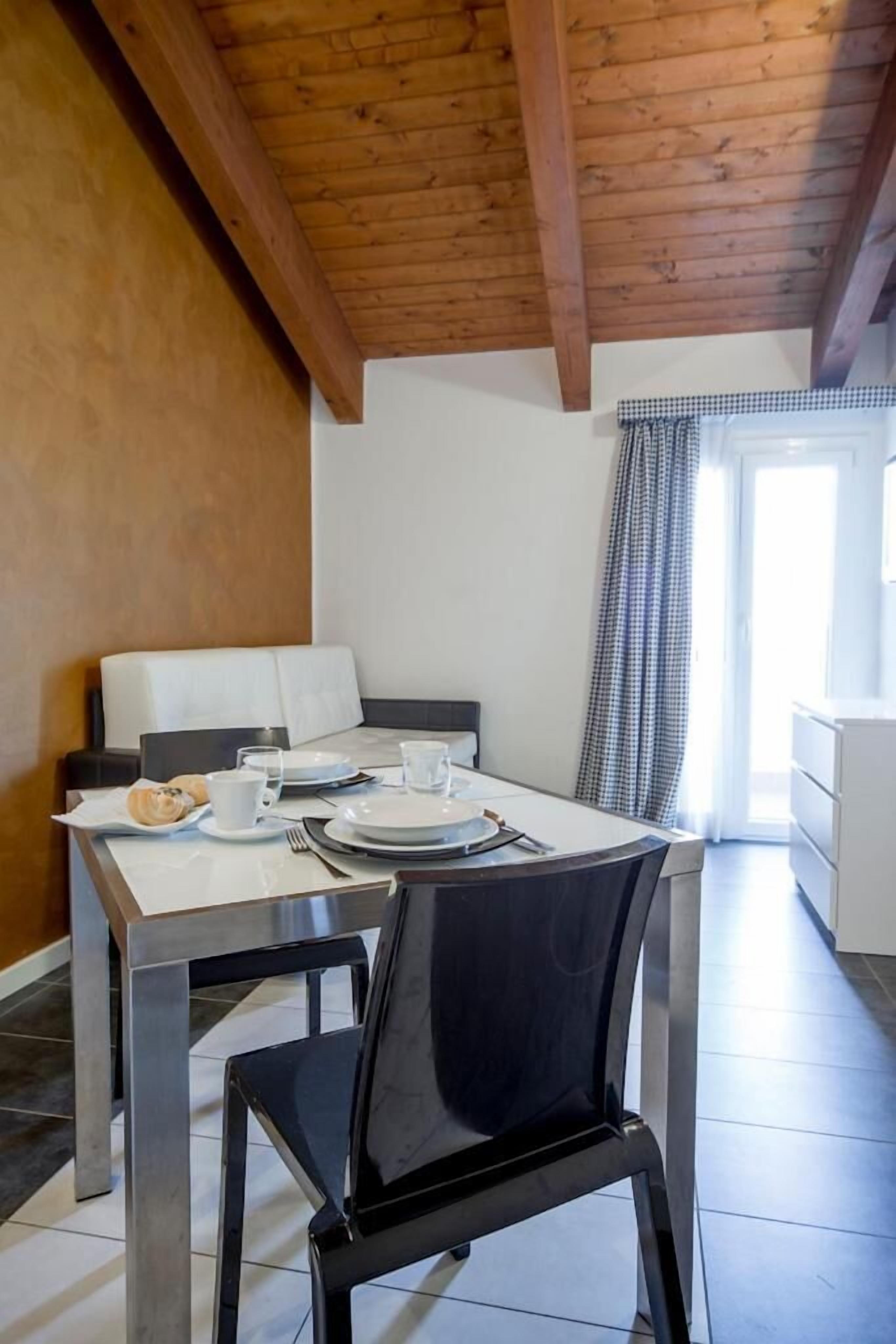 A dining area with a wooden ceiling, white walls, and a checkered curtain.