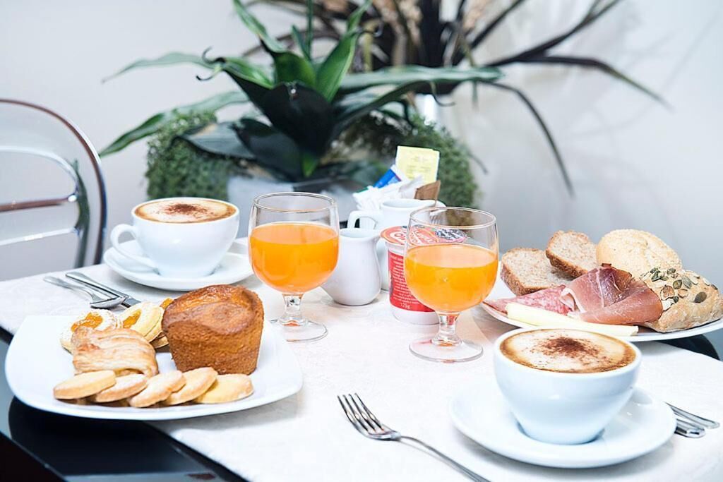 A breakfast setting with coffee, orange juice, pastries, and bread on a table.